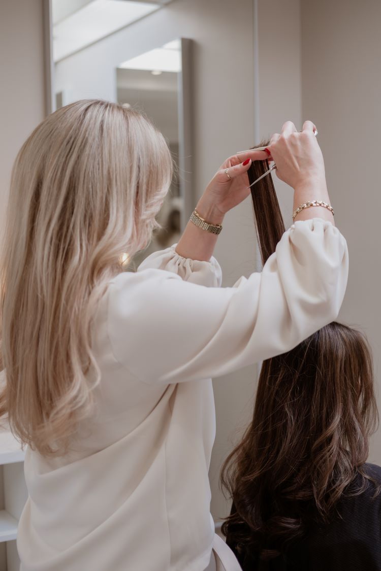 Het haar van een vrouw wordt door een teamlid geknipt